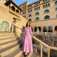 Model in a pink women's elegant long dress standing on stairs at a stunning historic venue