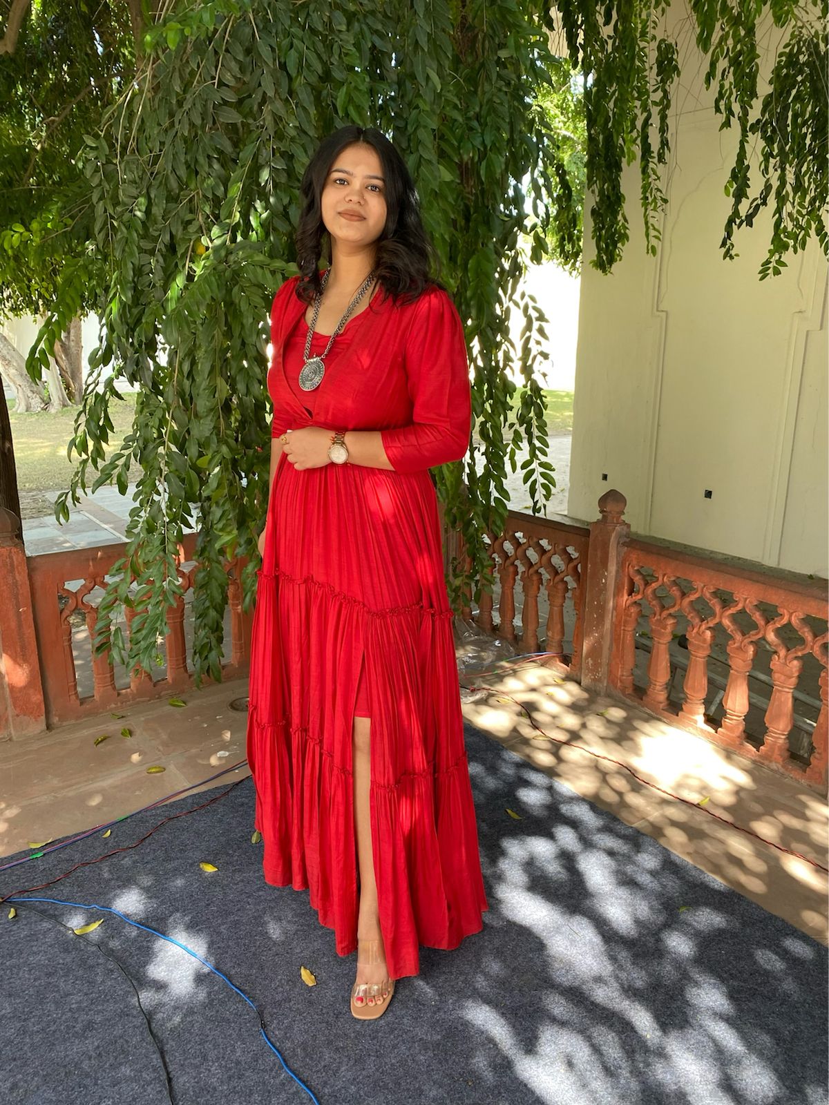 Model wearing a vibrant red women's elegant long dress with tiered design and a thigh slit