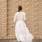 Back view of a women's elegant long dress by Stylera, featuring a flowy silhouette and tiered design