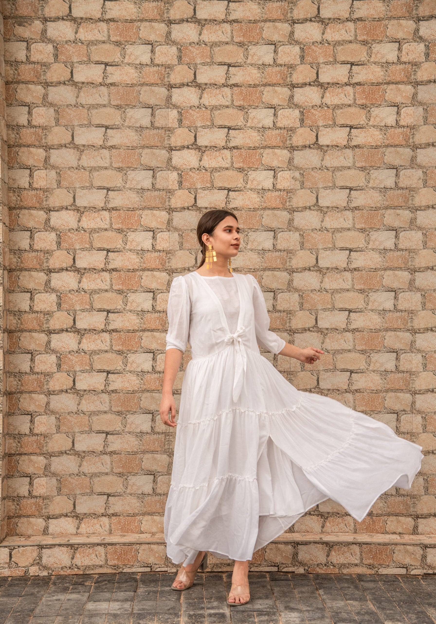 Model wearing a women's elegant long dress with tiered design and flowing fabric, perfect for formal occasions