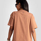 Back view of womens graphic oversized mocha tee by Stylera worn with sunglasses and watch