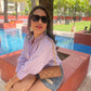 Model wearing a women's lightweight linen shirt in lavender shade with sunglasses and denim shorts