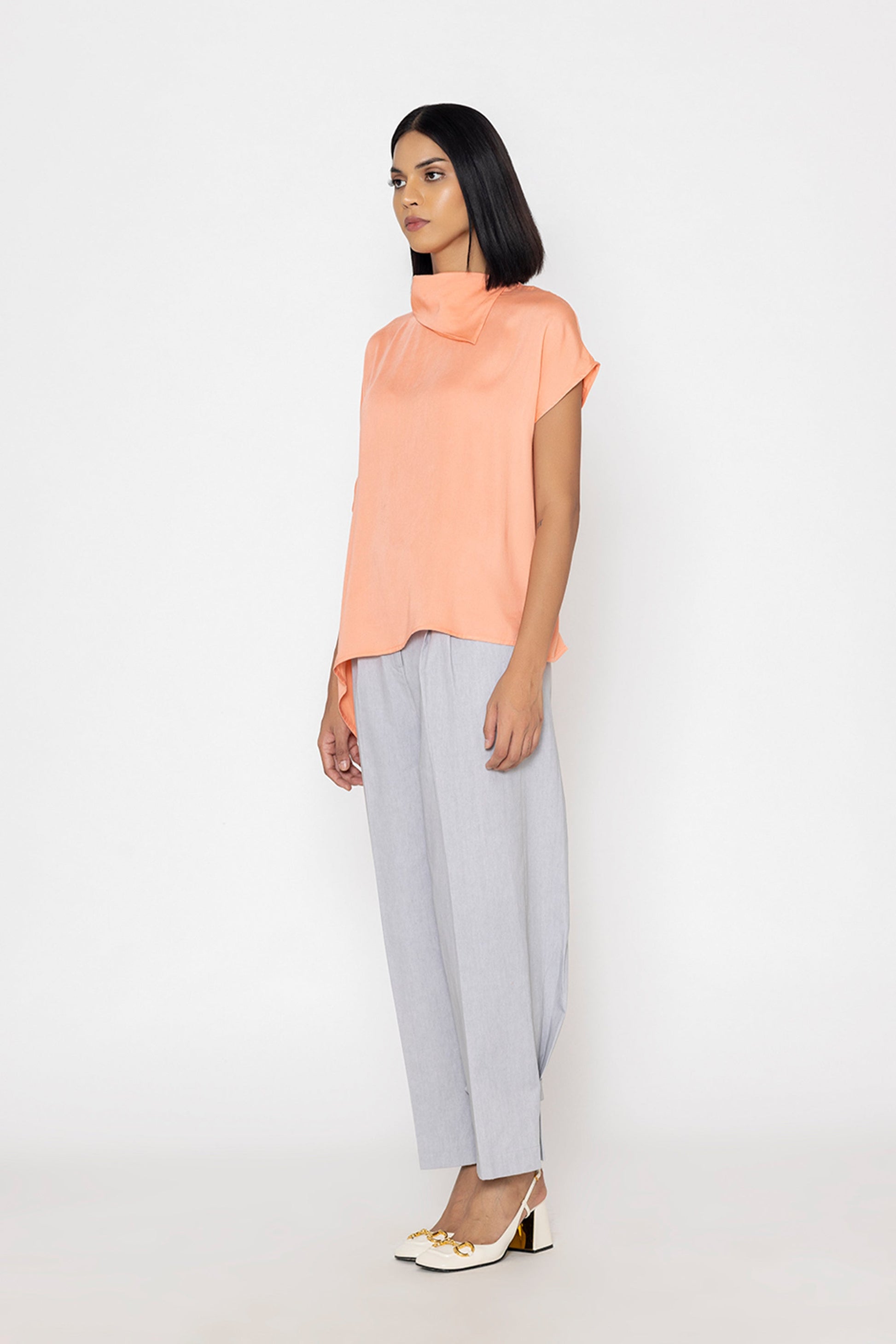 Stylera women's peach blouse with short sleeves and high neckline paired with light gray pants