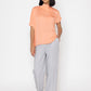 Stylera women's peach blouse with short sleeves and draped neckline styled with gray pants