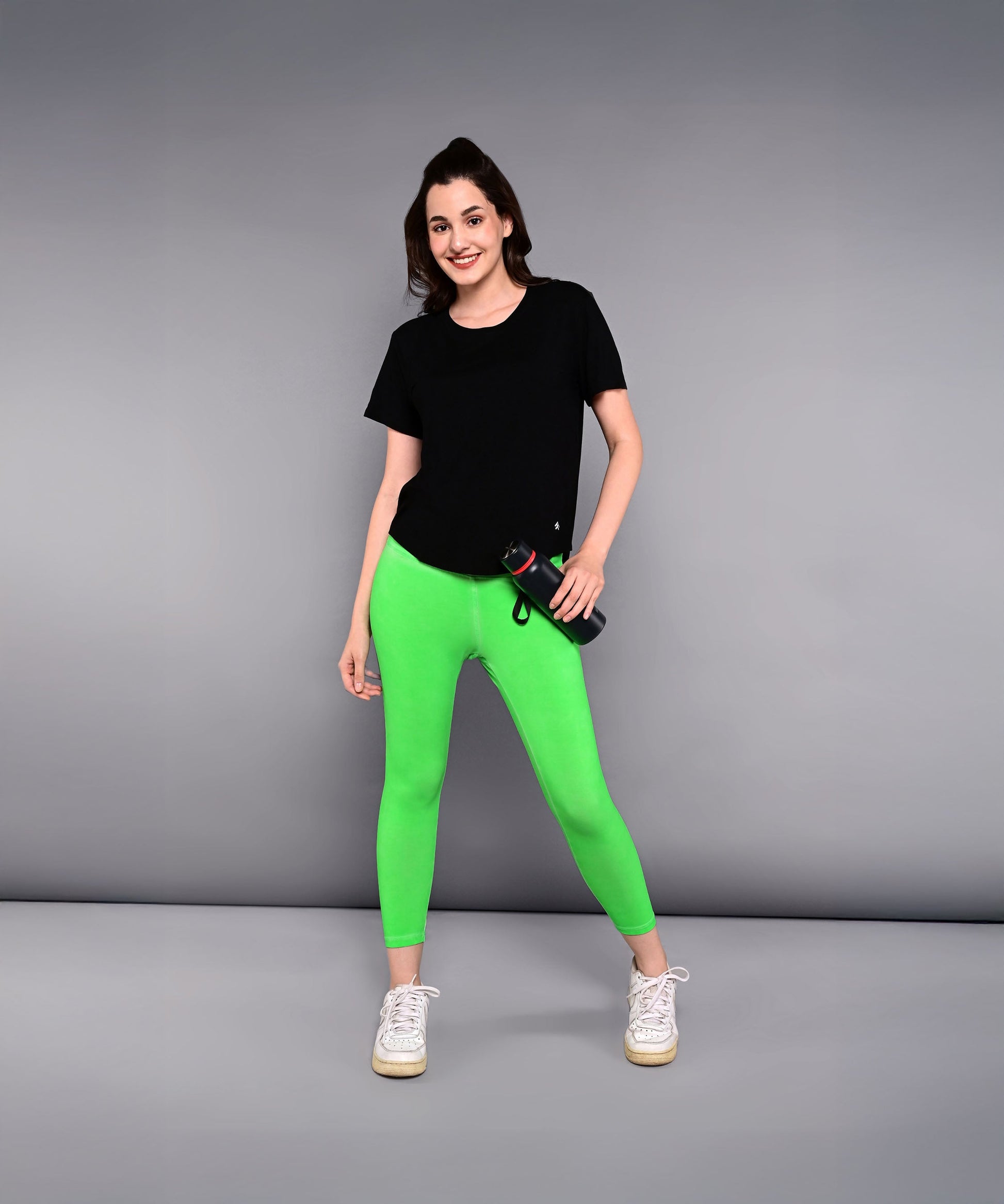 Stylera women's Pilates exercise top in black paired with bright green leggings for comfortable workouts
