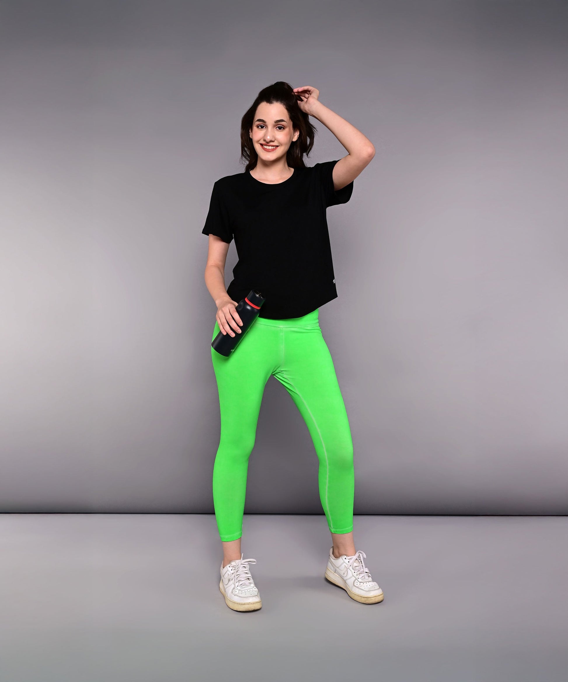 Stylera women's Pilates exercise top in black paired with vibrant green leggings for workout comfort