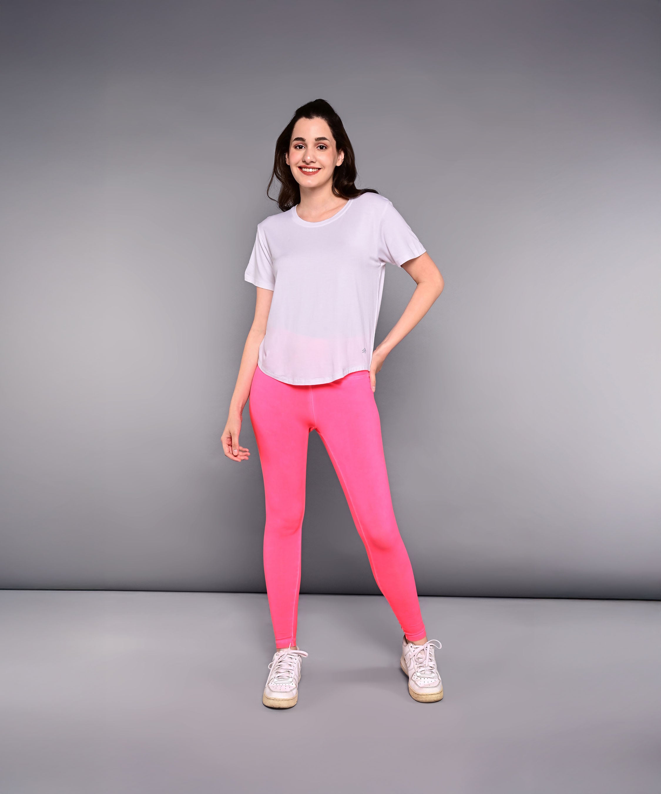 Stylish women's Pilates exercise top in white, paired with pink leggings for workout comfort