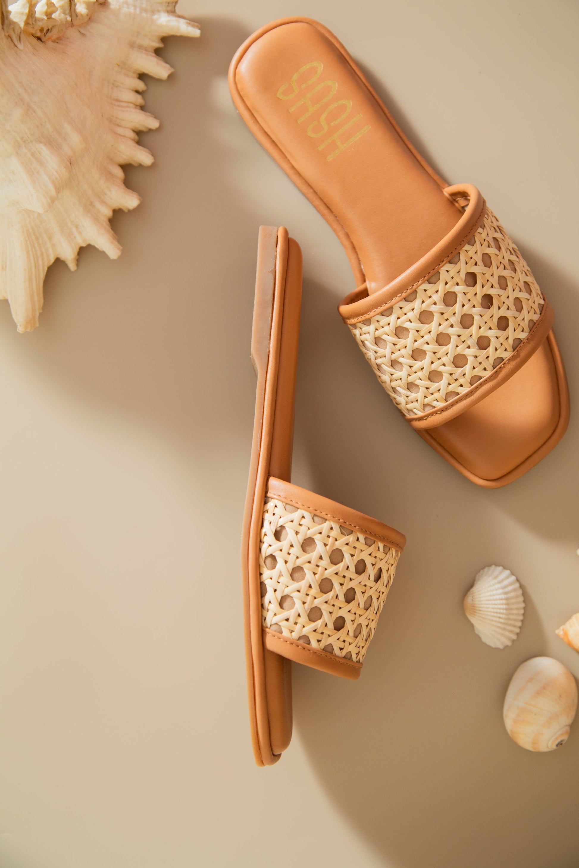 Stylera women's summer flat sandals with woven rattan strap and tan sole on beige background