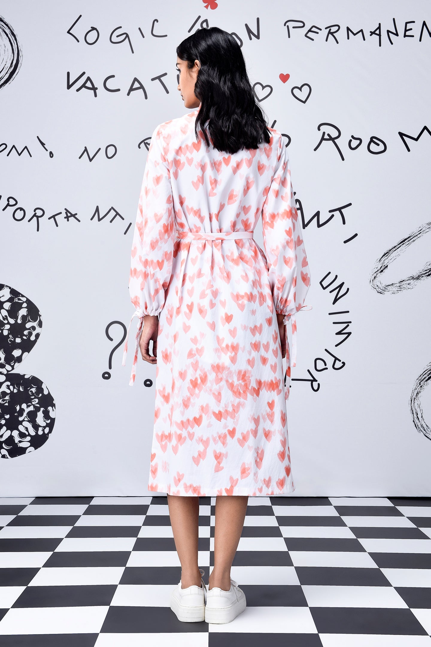 Back view of model wearing Stylera's women's trendy peach dress with belt long sleeves and heart print