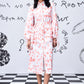 Model wearing women's trendy peach dress by Stylera collared long sleeve midi with tie waist and white sneakers