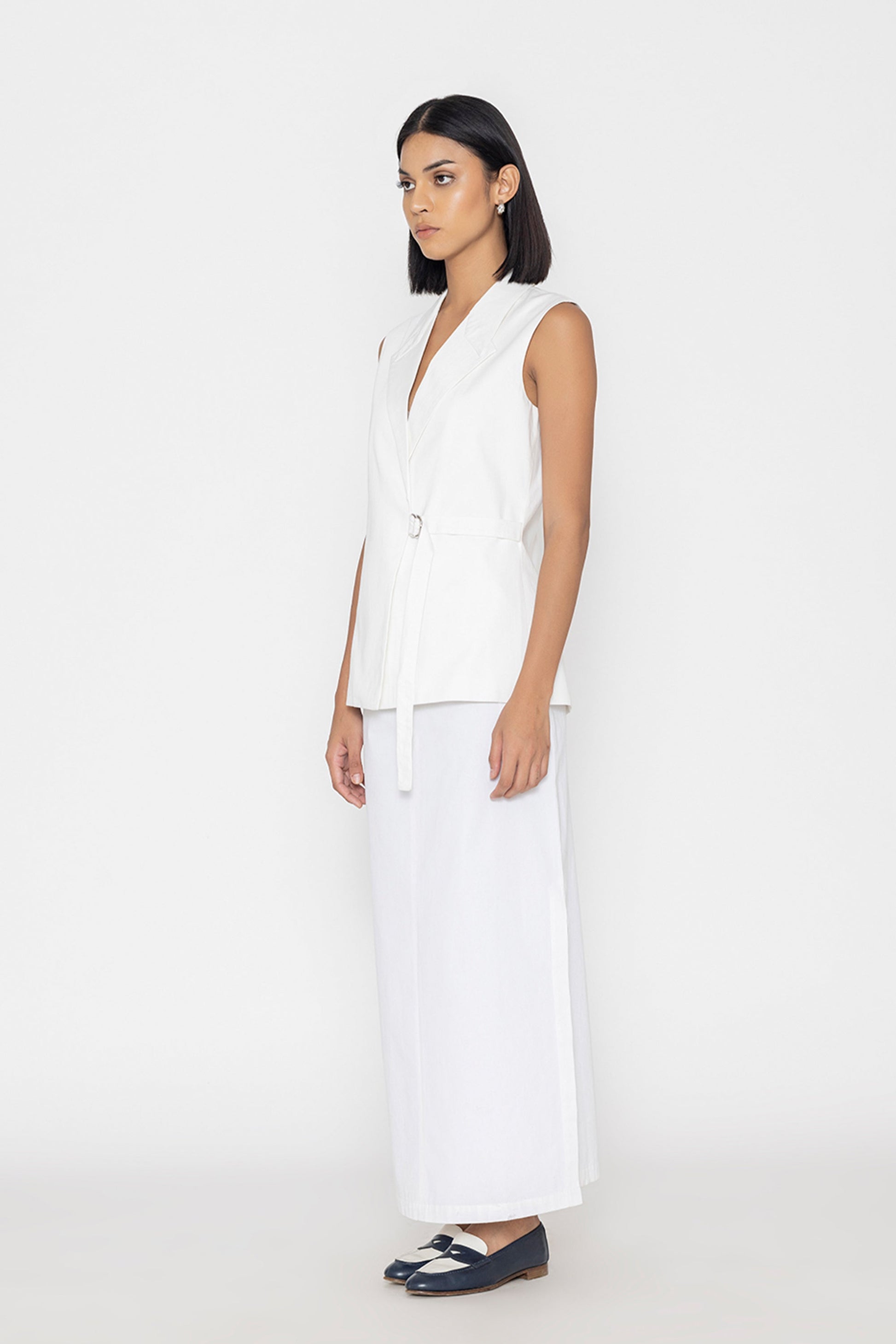 Stylera women's white sleeveless vest with belt detail styled with white skirt and black shoes