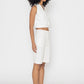 Model wearing Stylera women's white vest top paired with white shorts and sneakers