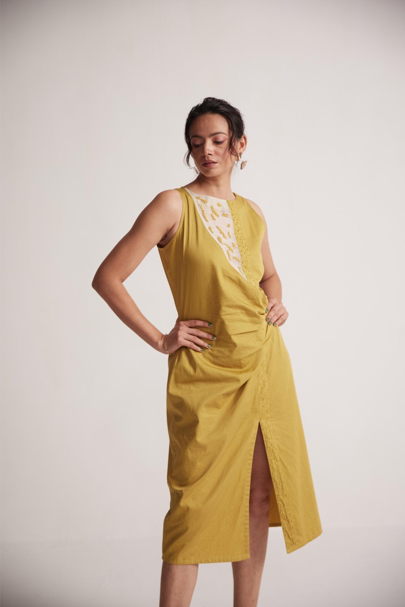 Stylera yellow draped midi dress with sleeveless design and front slit worn by a model