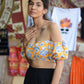 Woman wearing yellow floral off shoulder crop top with puff sleeves and black skirt