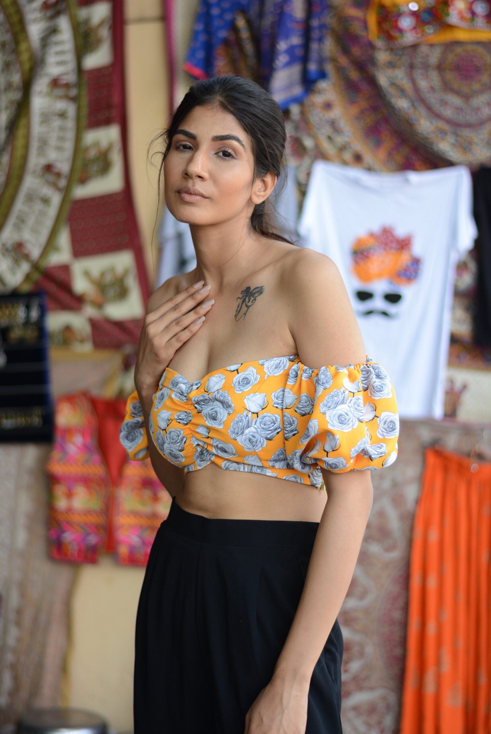 Woman wearing yellow floral off shoulder crop top with puff sleeves and black skirt