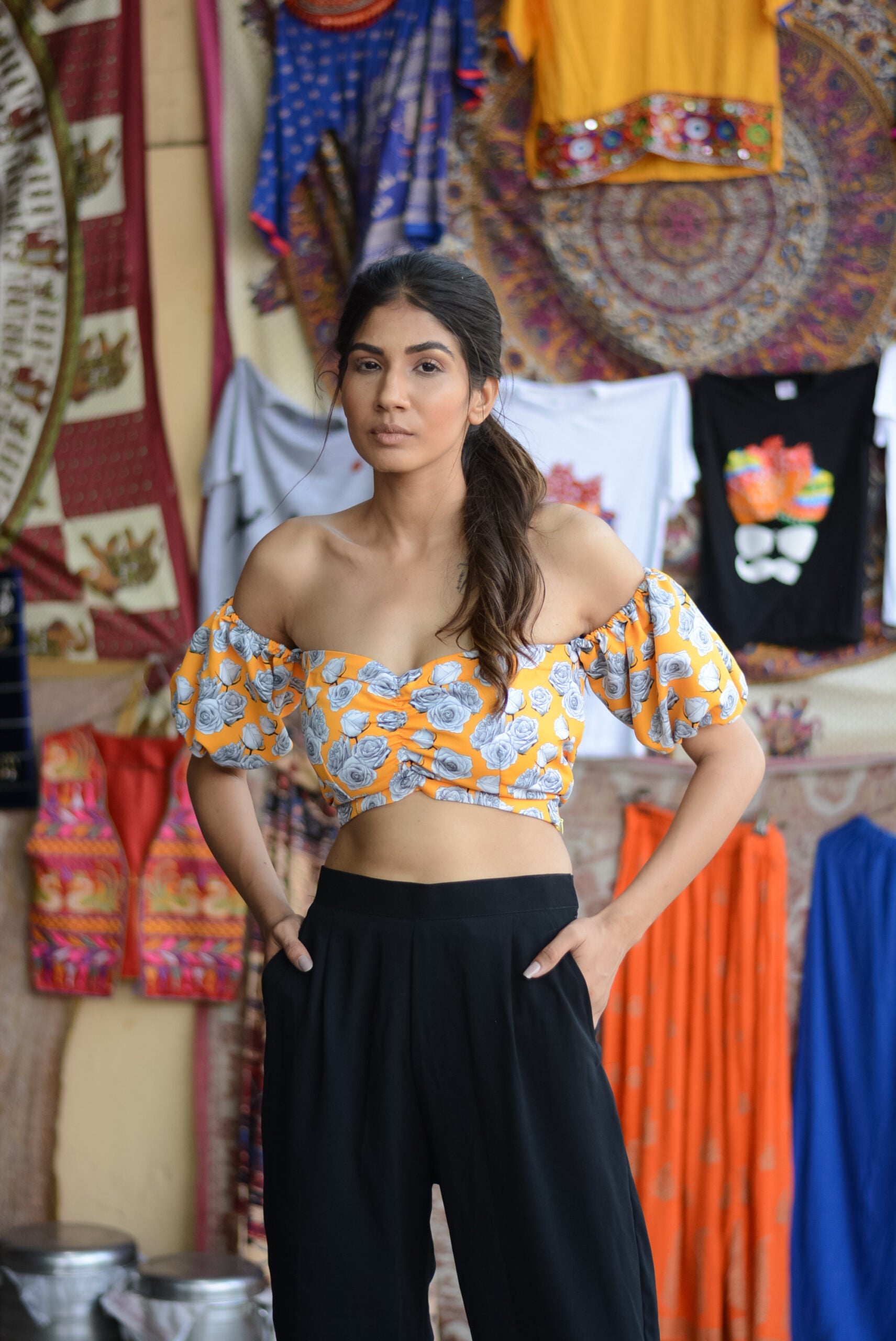 Woman wearing yellow floral off shoulder crop top with puff sleeves paired with black pants