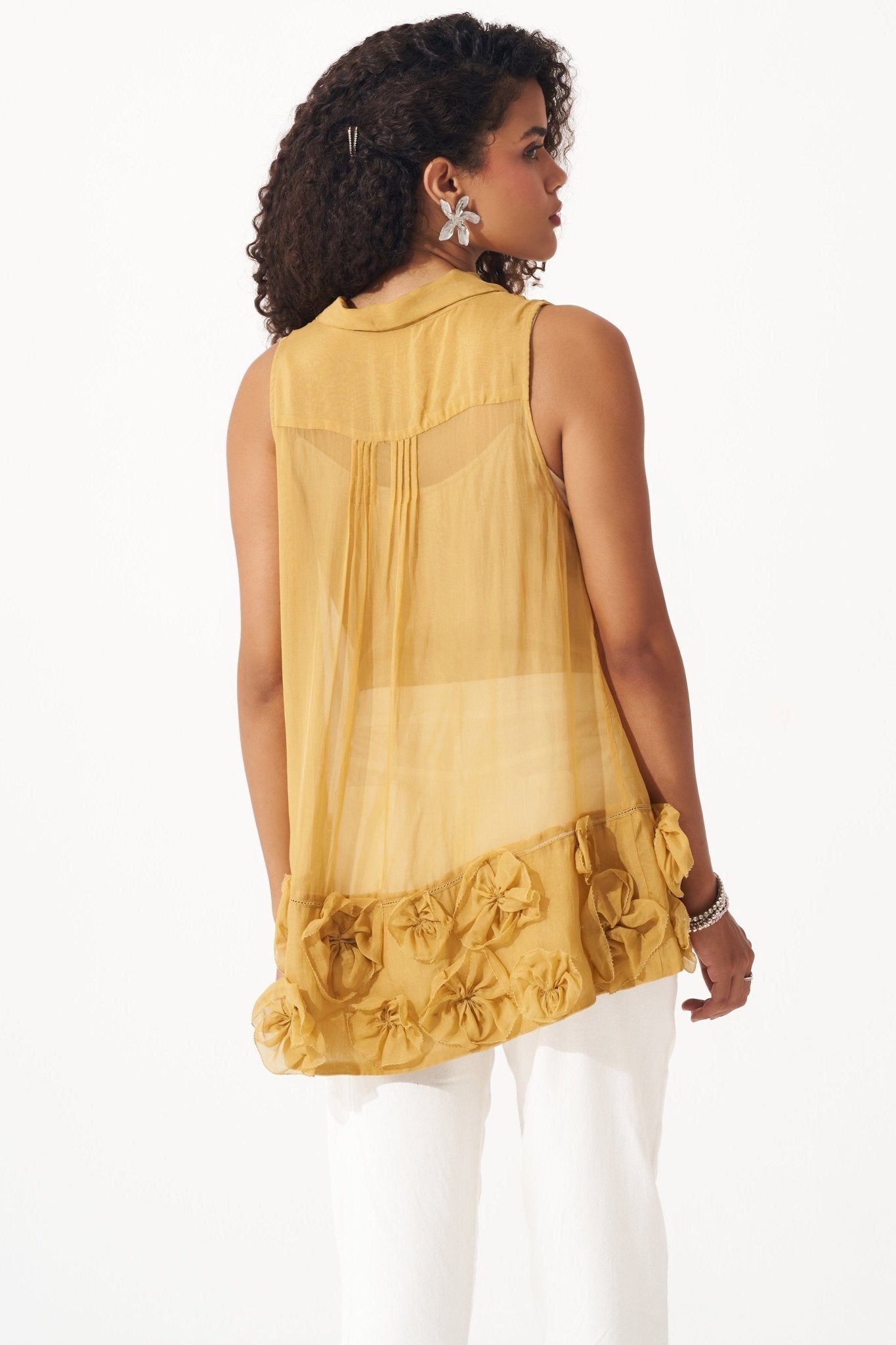 Stylera yellow organza sleeveless shirt with floral appliques on hem worn by woman
