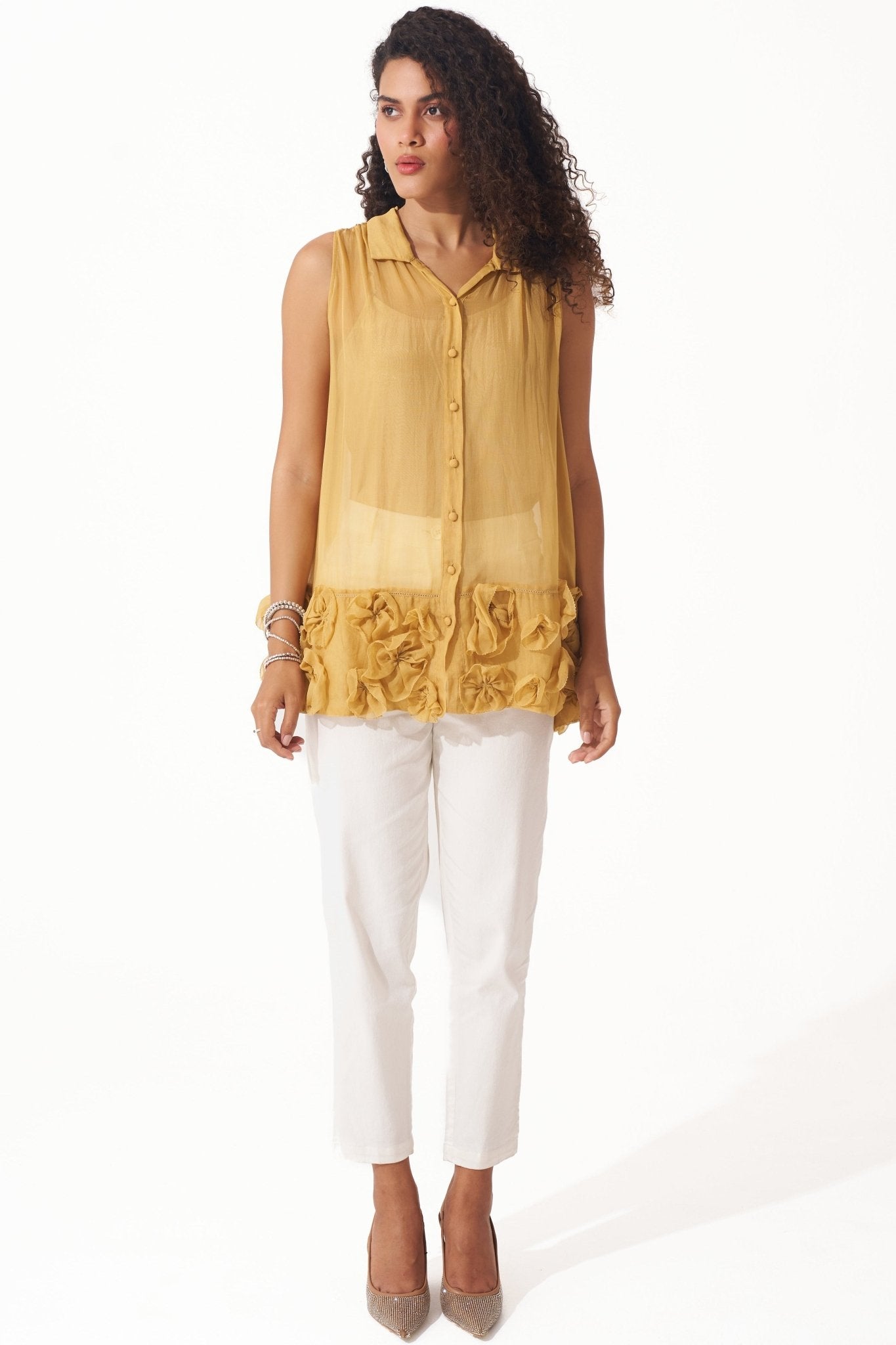 Stylera yellow organza sleeveless shirt with button front and floral ruffle detailing worn with white pants