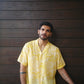 Casual model wearing a yellow oversize shirt for men against a wooden background