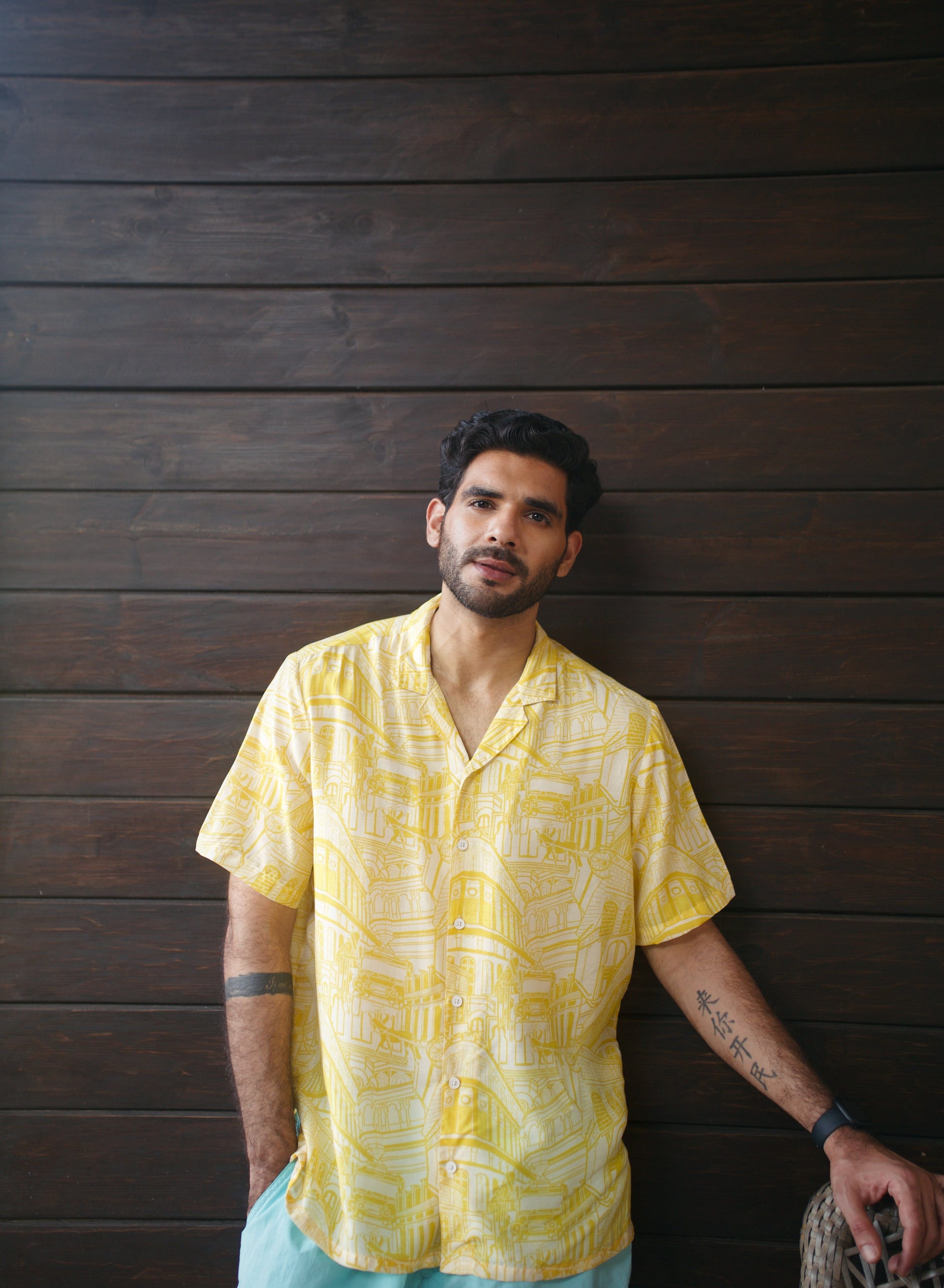 Casual model wearing a yellow oversize shirt for men against a wooden background