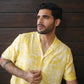 Stylish model wearing a yellow oversize shirt for men with a trendy pattern against a dark wood background