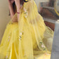 Elegant yellow sunflower saree with floral embroidery, styled gracefully on a model sitting on stairs