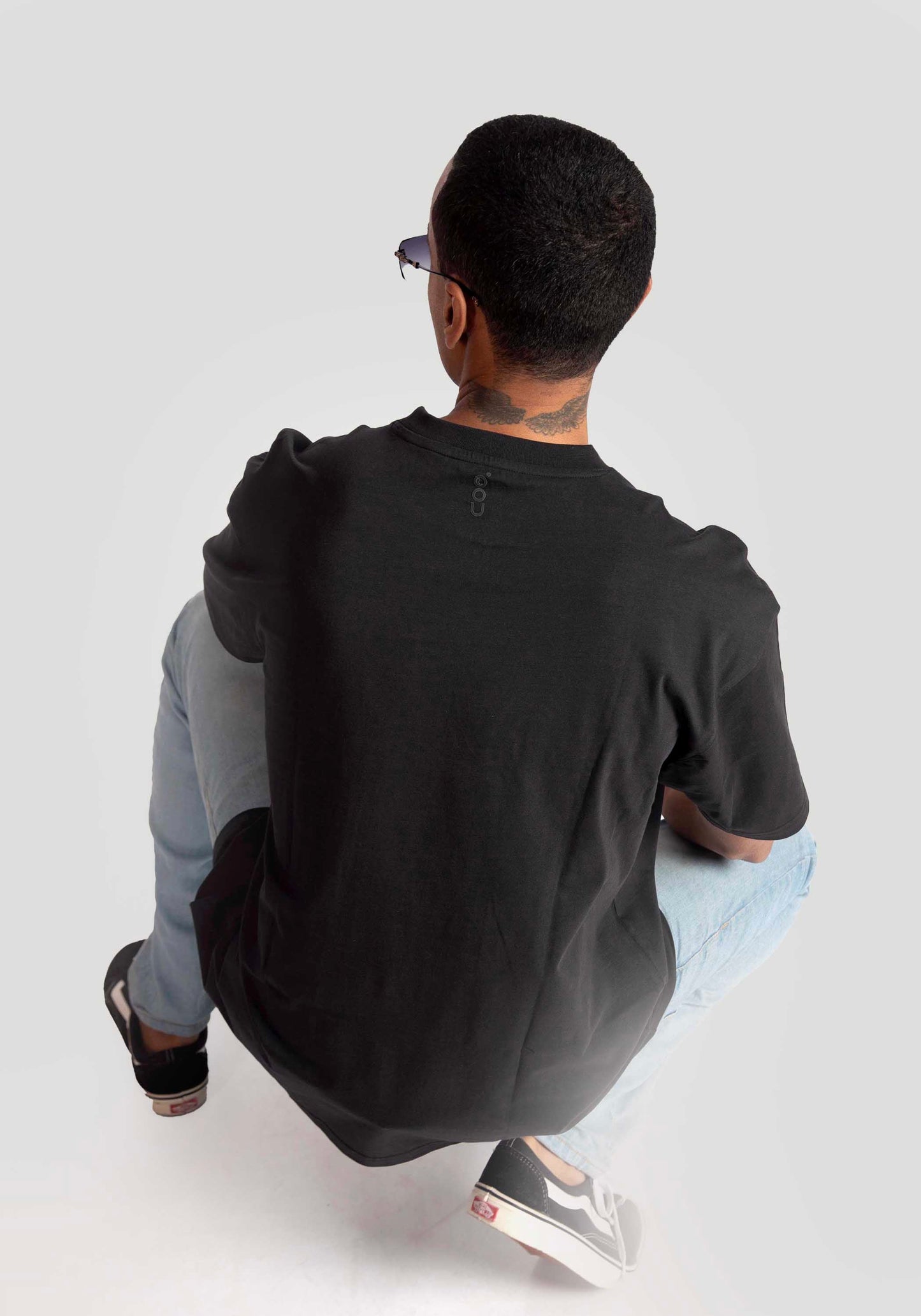 Man wearing black oversized graphic t-shirt from Stylera Lifestyle paired with light blue jeans and black sneakers