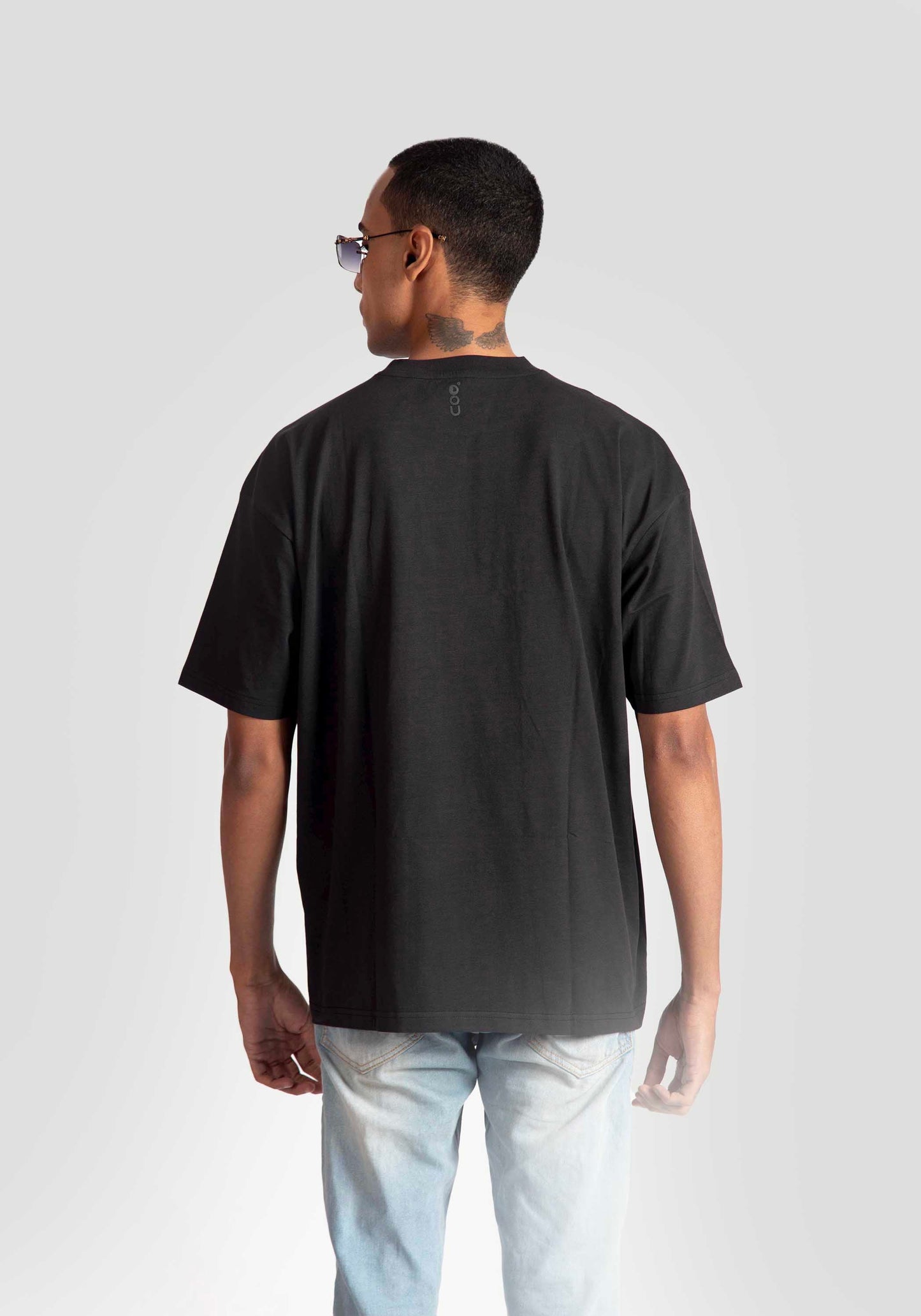 Rear view of a man wearing a black oversized graphic t-shirt with light blue jeans by Stylera Lifestyle